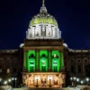 Image of the Pennsylvania state capitol building lighted in green