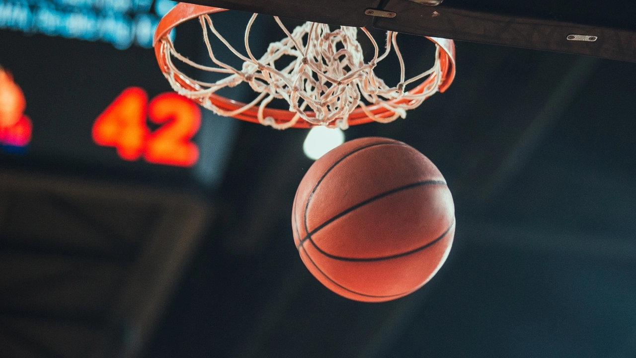 Image of a basketball going through a hoop with a scoreboard in the background