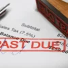 Image of a pen and Past Due stamp sitting atop a payment voucher