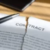 Image of a pen sitting atop a contract that is torn in two from the top