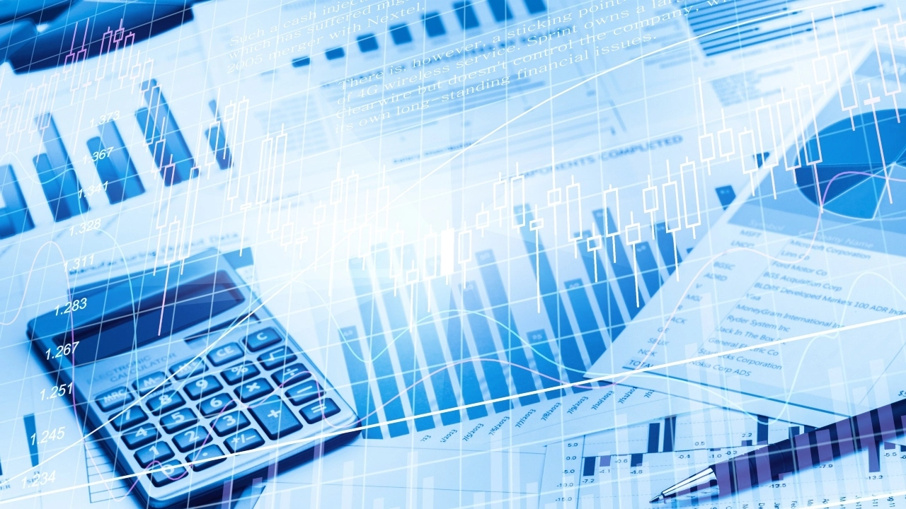 Image of a calculator and pen sitting atop business graphs and charts