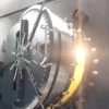 Image of a partially open bank vault door with a glowing light emanating from within