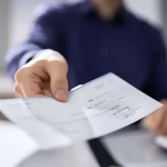 Image of a check being handed toward the veiwer