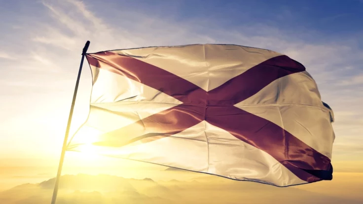 Image of the Alabama state flag waving amid a sunrise