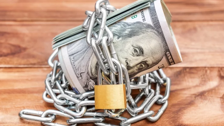 Image of rolled-up money shackled in chain and padlock