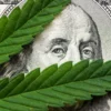 Close-up image of a $100 bill with Ben Franklin's eyes peaking through a cannabis leaf