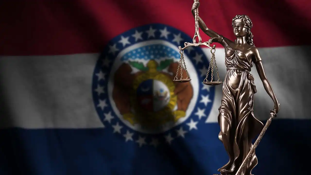 Image of Lady of Justice holding scales in front of Missouri state flag