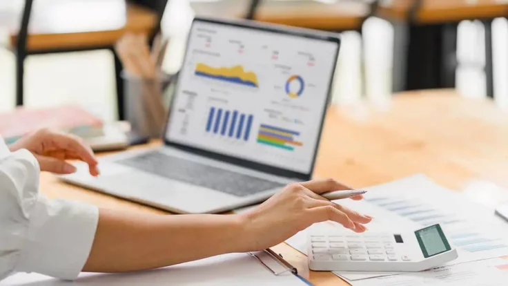 Image of person entering calculations on laptop.