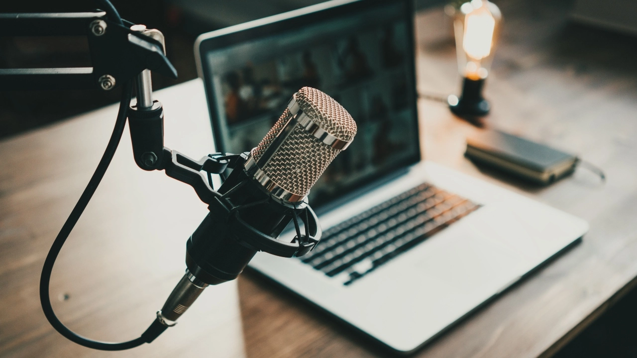 Close-up image of podcast equipment, including a microphone, laptop and an on-air lamp
