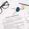 Image of a pair of eyeglasses, keys, pen and latptop sitting atop a lease agreement