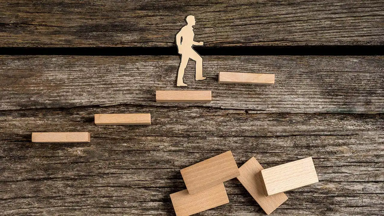 Image of a wooden silhouette of a person climbing corporate steps