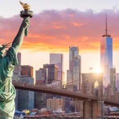 Image of the Statue of Liberty facing New York City at sunset