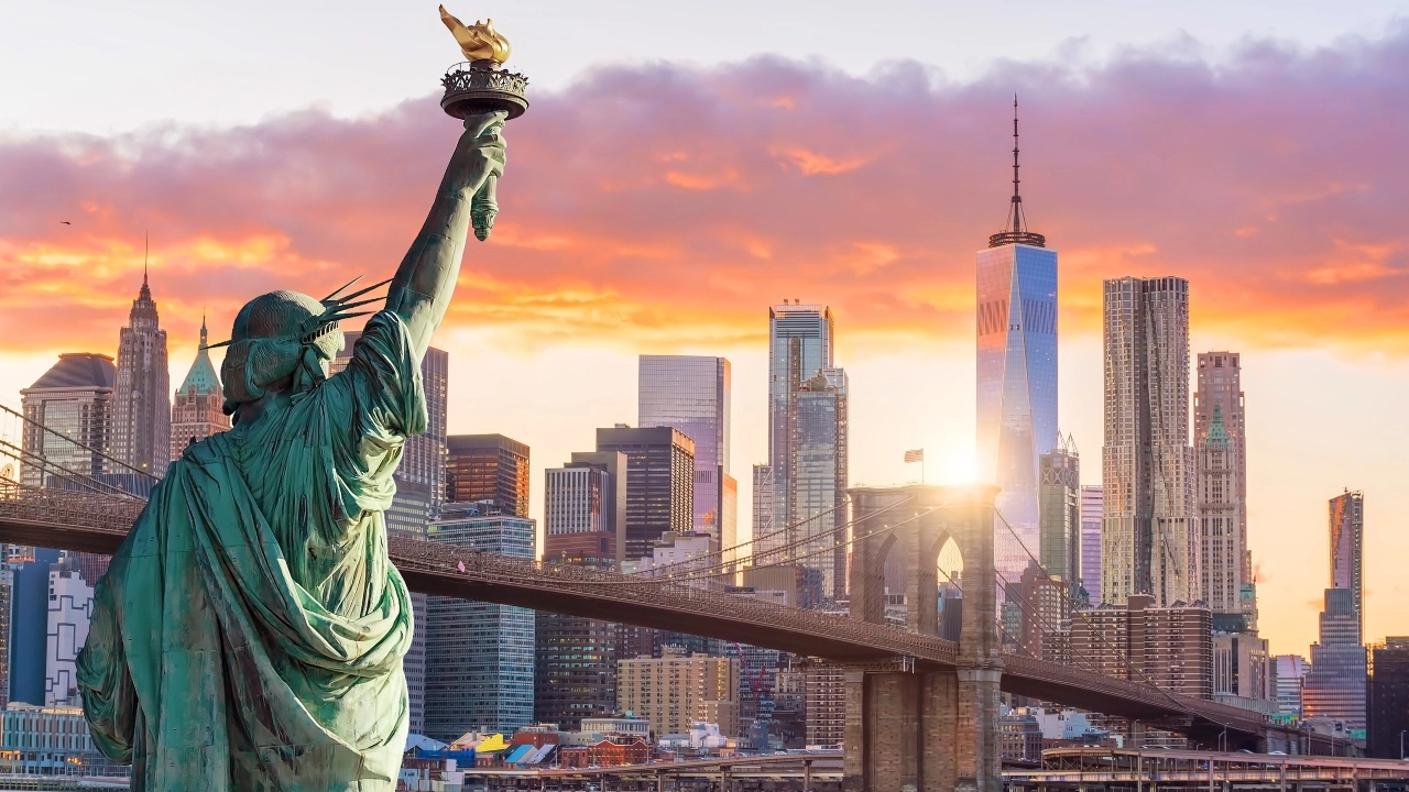 Image of the Statue of Liberty facing New York City at sunset