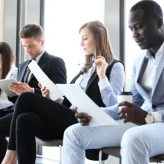 Image of five seated job applicants awaiting interviews