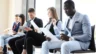 Image of five seated job applicants awaiting interviews