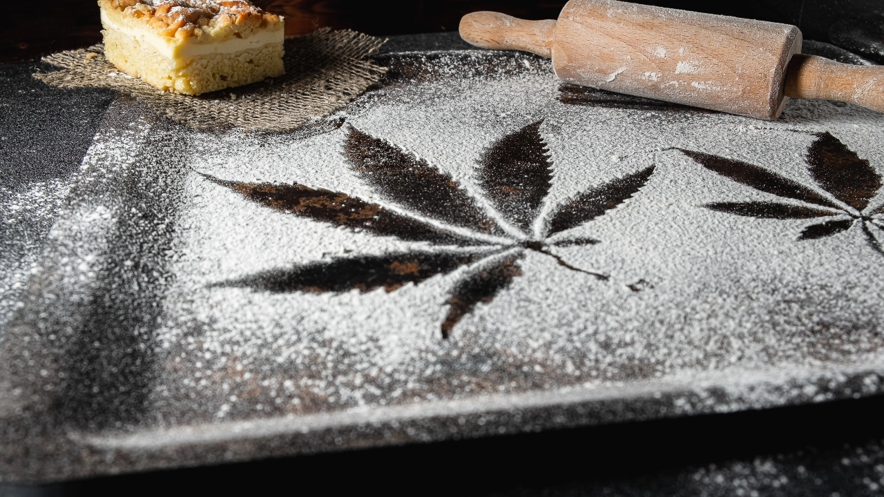Image of a cannabis leaf formed in white flower with a rolling pin and dessert adjacent