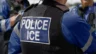 Image of the back of an ICE officer standing with fellow officers at the scene of an incident
