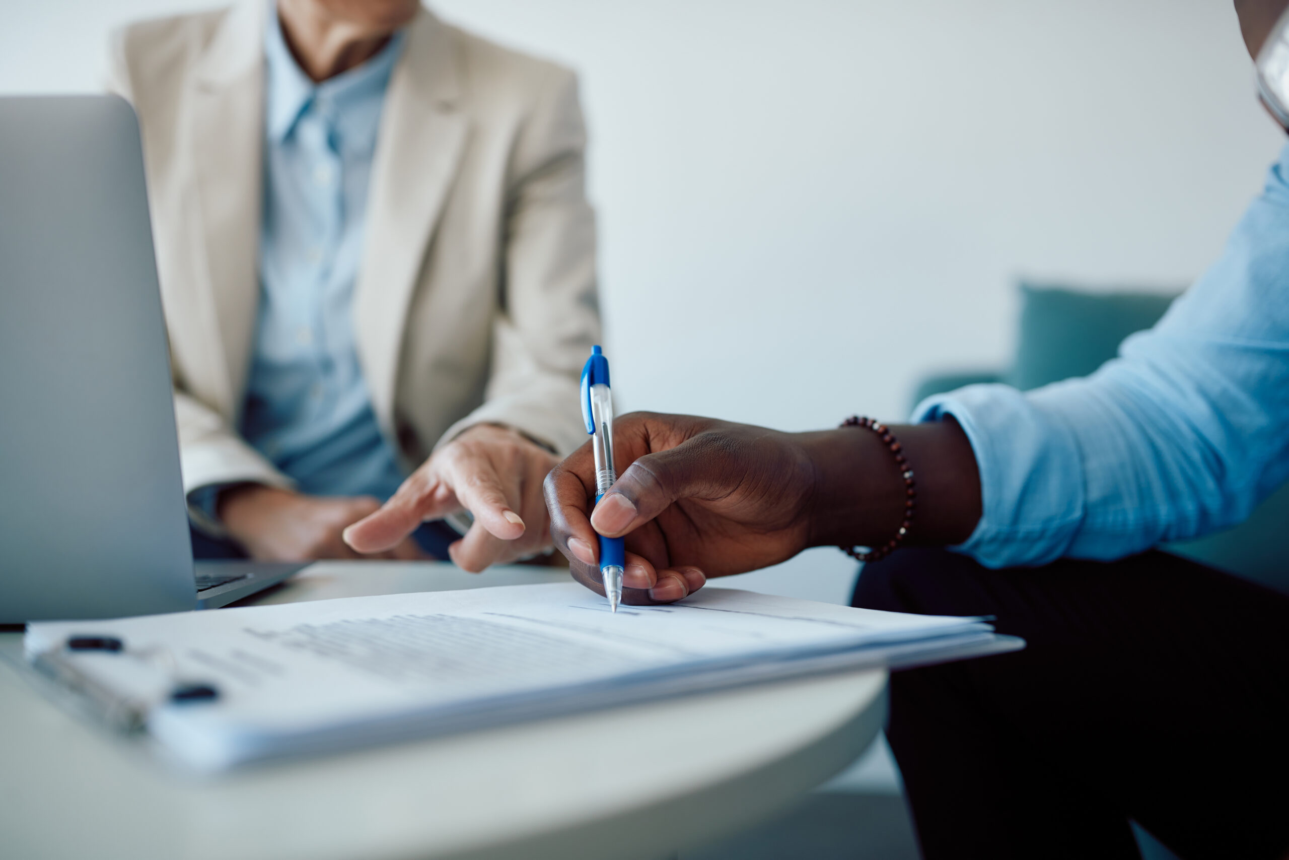 Close-up of black man signing contract with insurance agent in the office.